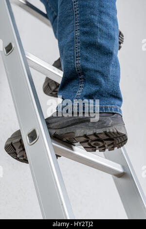 Un uomo in piedi su una scala a pioli Foto Stock