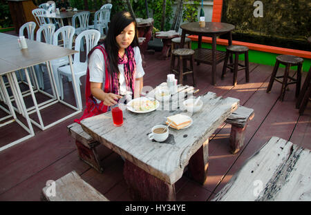 Asia donna tailandese di consumare la colazione in mattina tempo sul tavolo di legno al ristorante in hotel Foto Stock