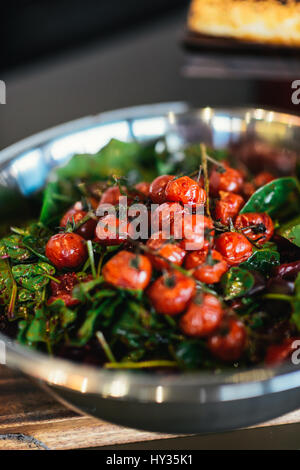 Arrosto di pomodori ciliegia sulla vite in una ciotola di metallo Foto Stock