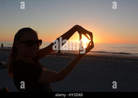 Tramonto sulla spiaggia con mom azienda sun in mano Foto Stock