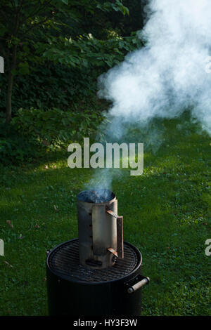 Carbone di legna camino ha iniziato a fumare a backyard grill. Foto Stock