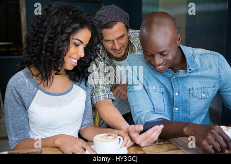 Multi etnico maschio e femmina amici utilizzando il telefono cellulare nel coffee shop Foto Stock