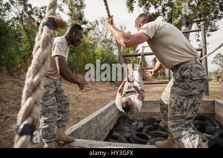 I giovani soldati militari la pratica di arrampicata corda durante la corsa a ostacoli al boot camp Foto Stock