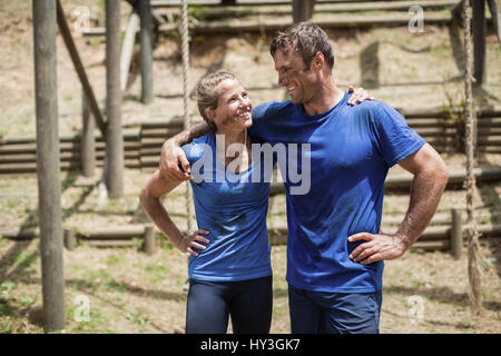 Uomo sorridente e donna in piedi con il braccio attorno a ciascun altro in boot camp Foto Stock