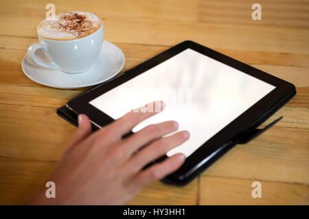 Close-up di donna mano con tavoletta digitale con schermo vuoto dalla tazza di caffè nella caffetteria Foto Stock