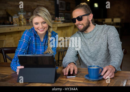 Sorridente coppia giovane utilizzando computer tablet a tavola in caffetteria Foto Stock