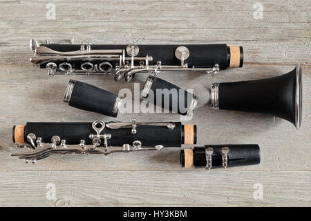 Vista dall'alto di un nero clarinetto smontabile in quattro parti su un alterato grigio Sfondo di legno Foto Stock
