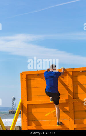 Scavalcando il cliffhanger ostacolo, parte della tempesta di sabbia spiaggia sfida, sul Bournemouth Beach, un Beach Assault Course in Marzo Foto Stock