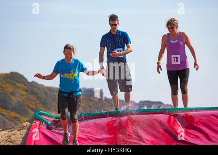 I partecipanti alla sommità del scivolo slitta sfida, parte della tempesta di sabbia spiaggia sfida, sul Bournemouth Beach, un Beach Assault Course in Marzo Foto Stock