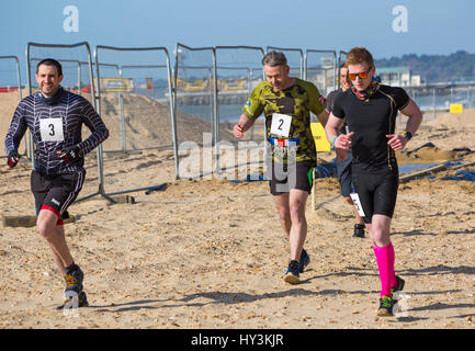 Gli uomini che partecipano nella tempesta di sabbia sfida a Bournemouth in Marzo Foto Stock