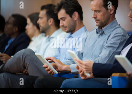 I dirigenti aziendali che partecipano a una riunione di affari con tavoletta digitale presso il centro conferenze Foto Stock