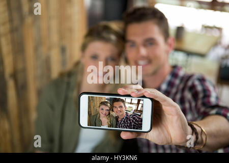 Sorridente coppia giovane tenendo selfie con cellulare nella caffetteria Foto Stock