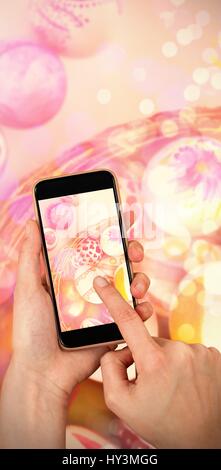 Cestino con il dipinto di uova di Pasqua su sfondo bianco contro le mani toccano smart phone Foto Stock