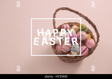 Saluto pasquale contro il cestello con dipinto di uova di pasqua su sfondo bianco Foto Stock