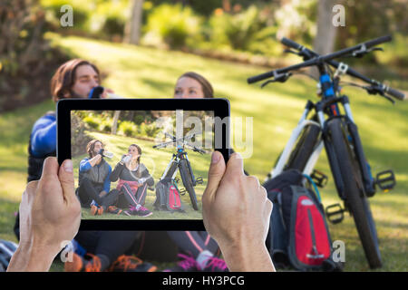 Ritagliato mano azienda digitale compressa contro il biker giovane rilassante e avente acqua Foto Stock