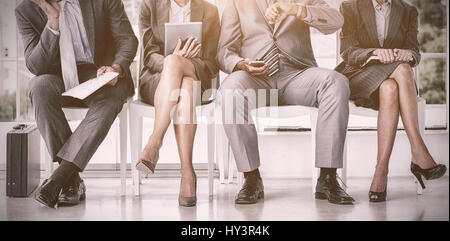 La gente di affari in attesa di essere chiamato in colloquio presso l'ufficio Foto Stock