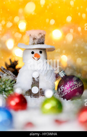 Pallina di natale con etichetta felice Natale e pupazzo di neve, Weihnachtskugel mit Aufschrift Frohe Weihnachten und Schneemann Foto Stock