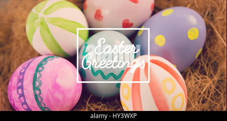 Saluto pasquale contro il dipinto di uova di pasqua nel nido Foto Stock