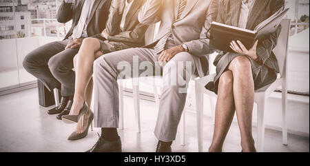 Ben vestito la gente di affari in attesa di essere chiamati per il colloquio in ufficio Foto Stock