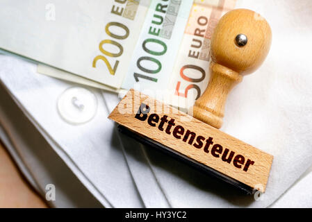 Timbro con etichetta letto-costosi e banconote su un foglio, Stempel mit Aufschrift Bettensteuer und Geldscheine auf einem Bettlaken Foto Stock