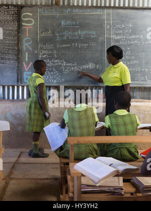 Un insegnante in corrispondenza di un ponte Accademie Internazionali scuola primaria a Mpigi, Uganda. Foto Stock