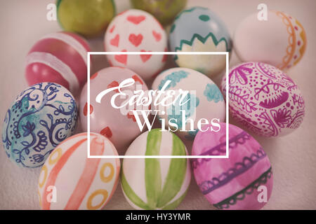 Saluto pasquale contro il dipinto di uova di pasqua su sfondo bianco Foto Stock