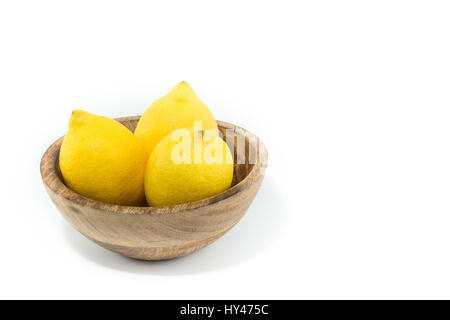 Tre limoni in una naturale fatta a mano in vero legno ciotola isolato in sfondo nero Foto Stock