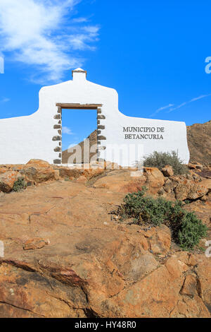 Comune tradizionale segno (bianco arch gate) vicino al villaggio di Betancuria con il paesaggio del deserto in background, Fuerteventura, Isole Canarie, Spagna Foto Stock