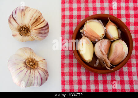 Angolo di alta vista di aglio e scalogno spicchi su un asciugamano rustico e sfondo bianco Foto Stock