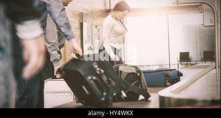 Le persone che trasportano bagagli dal reclamo bagagli in aeroporto Foto Stock