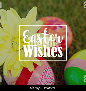 Saluto pasquale contro il dipinto di uova di Pasqua con i fiori di erba Foto Stock