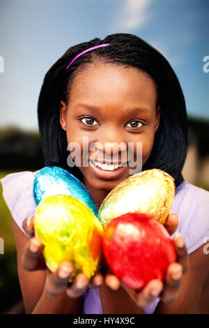 Strada fangosa dal campo erboso contro la donna attraente holding colorate uova di pasqua Foto Stock