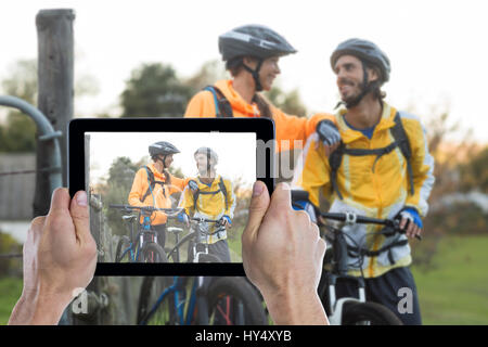 Ritagliato mano azienda digitale compressa contro il biker matura interazione permanente, mentre con mountain bike Foto Stock