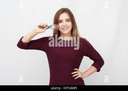 Close up volto di donna giovane pittore tenendo un pennello oltre il suo volto Foto Stock