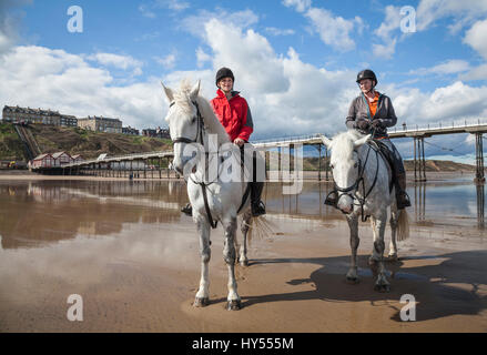 Due donne a cavallo sulla spiaggia di Saltburn,l'Inghilterra,UK Foto Stock