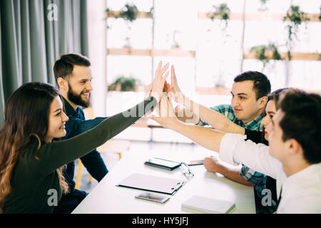 I colleghi dando ad alta cinque in una sala riunioni presso il creative office room Foto Stock