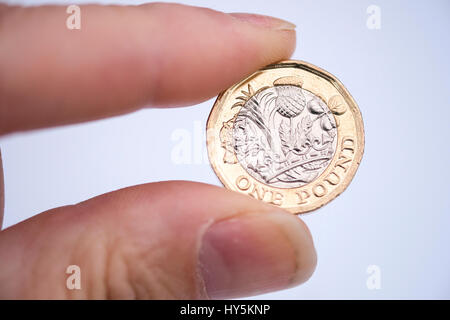 Dito e il pollice tenendo una sola lira coin Foto Stock