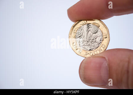 Dito e il pollice tenendo una sola lira coin Foto Stock