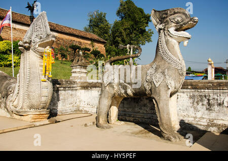 Singha o Lion guardian statue con naga scalinata sulla parte anteriore della porta entrane per chi va a piedi a pregare e visitare chedi di Wat Phra That Lampang Foto Stock