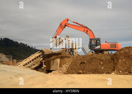 Un gold miner paydirt feed da una miniera a cielo aperto nella schermata che separerà i oro. Foto Stock