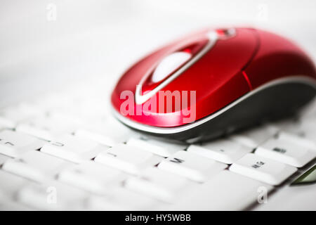 Un bel rosso mouse wireless sul bianco della tastiera di un computer portatile. Profondità di campo Foto Stock