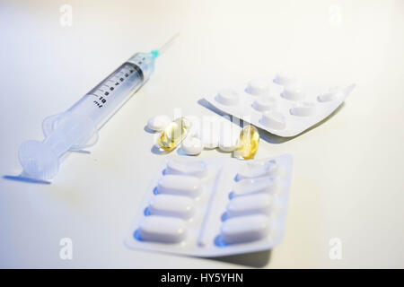 Una varietà di farmaci comprendente una siringa con una punta verde, confezione blister, pillole di bianco e giallo pillole di plastica piena di olio di fegato di merluzzo vitamina D suppl Foto Stock