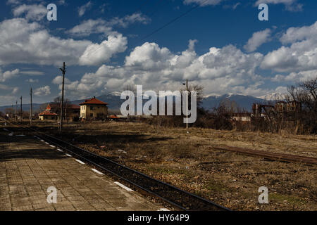 Vista della stazione di stretto-gage ferroviario con le montagne ricoperte di neve su uno sfondo Foto Stock