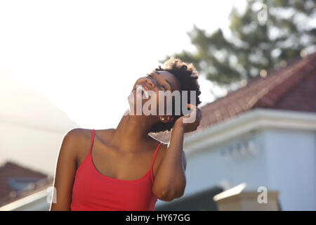 Close up ritratto di giovane donna nera ridendo all aperto con la sua mano nei capelli Foto Stock