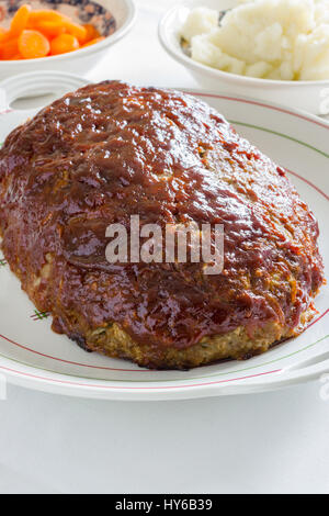 Classic American polpettone fatto con carne di manzo macinata farina di avena cipolle e un ketchup lo zucchero di canna e la senape smalto servita con purè di patate e carote coin Foto Stock