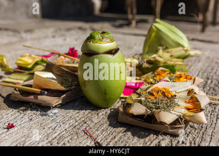 Offerte tradizionali per gli dèi di Bali con fiori, cibo e bastoni di aroma Foto Stock