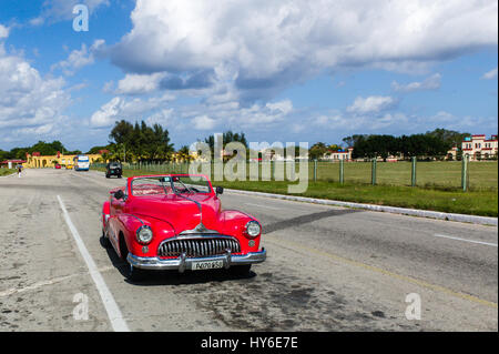 Classic rosso convertibili parcheggiato sulla strada di fronte ad una base militare a l'Avana, Cuba. Foto Stock