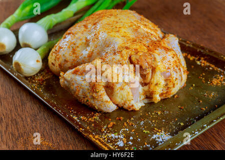 Pollo intero crudo stagionato nel vassoio da forno con un trito di verdure Carote Patate cipolle, rosmarino, tavolo da cucina e al procedimento di preparazione,vista superiore Foto Stock