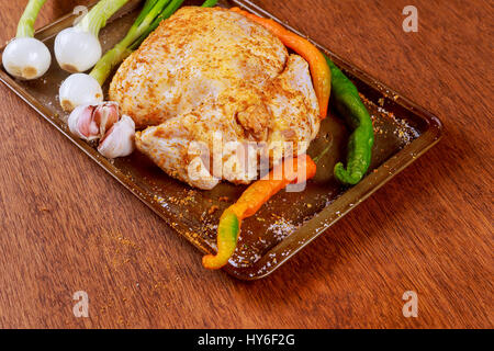 Non cotti di pollo intero in forma di cottura con un trito di verdure Carote Patate dolci cipolle, stagionati, preparato per la cottura Foto Stock