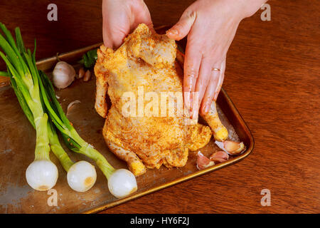 Tutto il pollo crudo sulla carta da forno con il condimento prima della cottura. Materie marinata di pollo intero cook Foto Stock